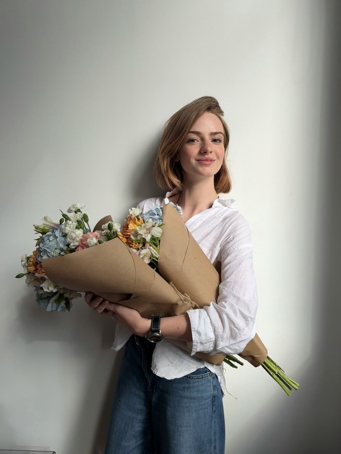 Madison Campbell wearing a white shirt and holding a bouquet of flowers